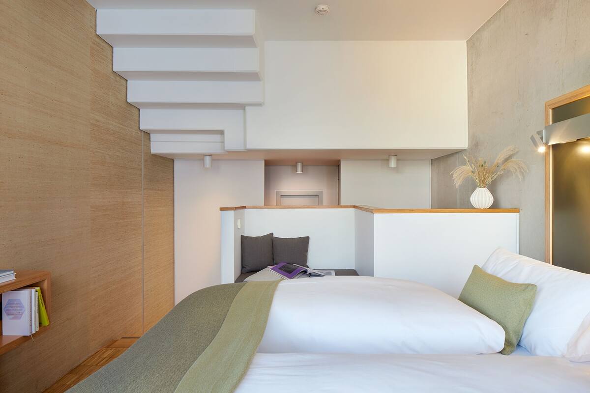 A modern bedroom with a bed, a small desk, and a bookshelf.