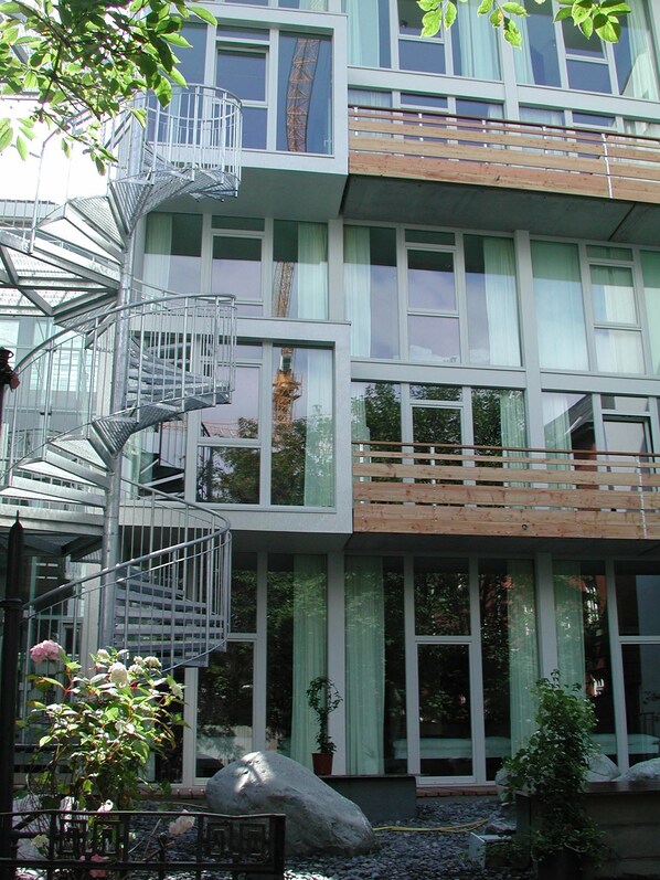 A modern building with a spiral staircase, large windows, and a stone feature in the foreground. - Wedina Serviced Apartments (Hamburg)