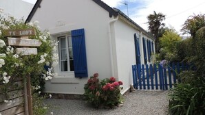 A white building with blue shutters, a gravel driveway, and a wooden fence.