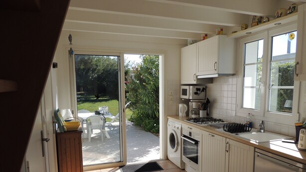 A kitchen with a washing machine, microwave, and sink.