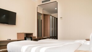 A hotel room with a large bed, a TV mounted on the wall, and a mirror reflecting the room. - Hotel Khanaka (Turkestan)