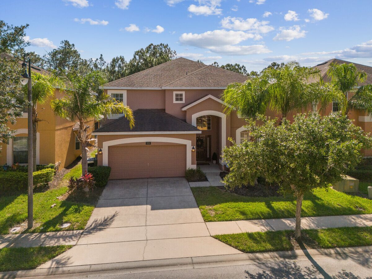 A single-story house with a garage, a front yard with trees, and a clear sky.