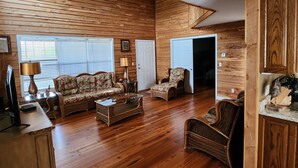 A spacious living room with wooden panel walls, a sofa, a chair, and a coffee table.