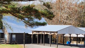 A rustic barn with a metal roof, open stalls, and a covered area with a wooden frame.