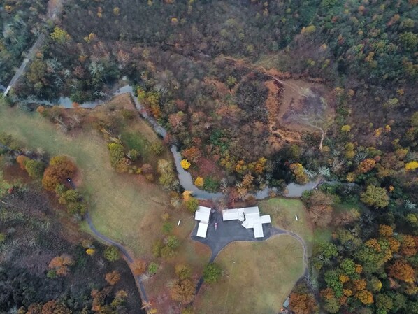 Vista aérea de una propiedad con un amplio campo abierto, un pequeño edificio y un sendero sinuoso.