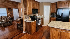 A kitchen with wooden cabinets, a stove, a microwave, and a refrigerator.