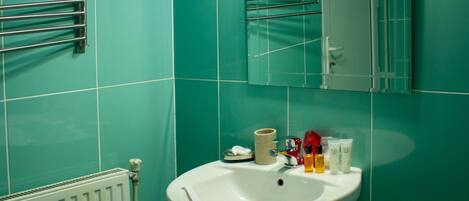 Un baño con paredes color turquesa, un lavamanos blanco y un espejo encima.