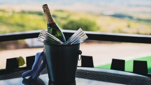 Um balde com uma garrafa de champanhe e um menu dobrado sobre uma mesa com vista para uma paisagem.