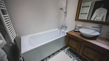 A bathroom with a bathtub, a sink, and a mirror.