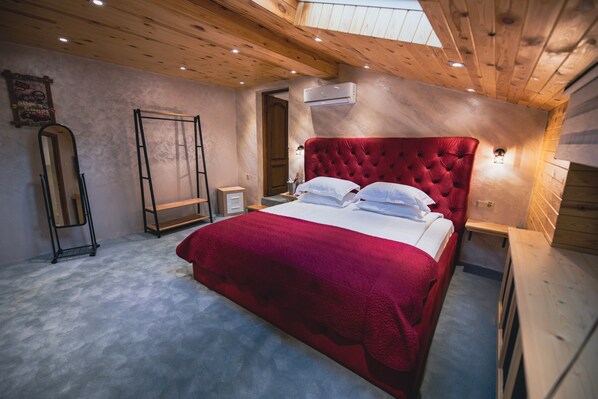 A bedroom with a large bed, wooden ceiling, and an air conditioning unit.