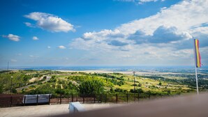 Vista panorâmica de uma varanda com vista para uma paisagem verde e uma bandeira.