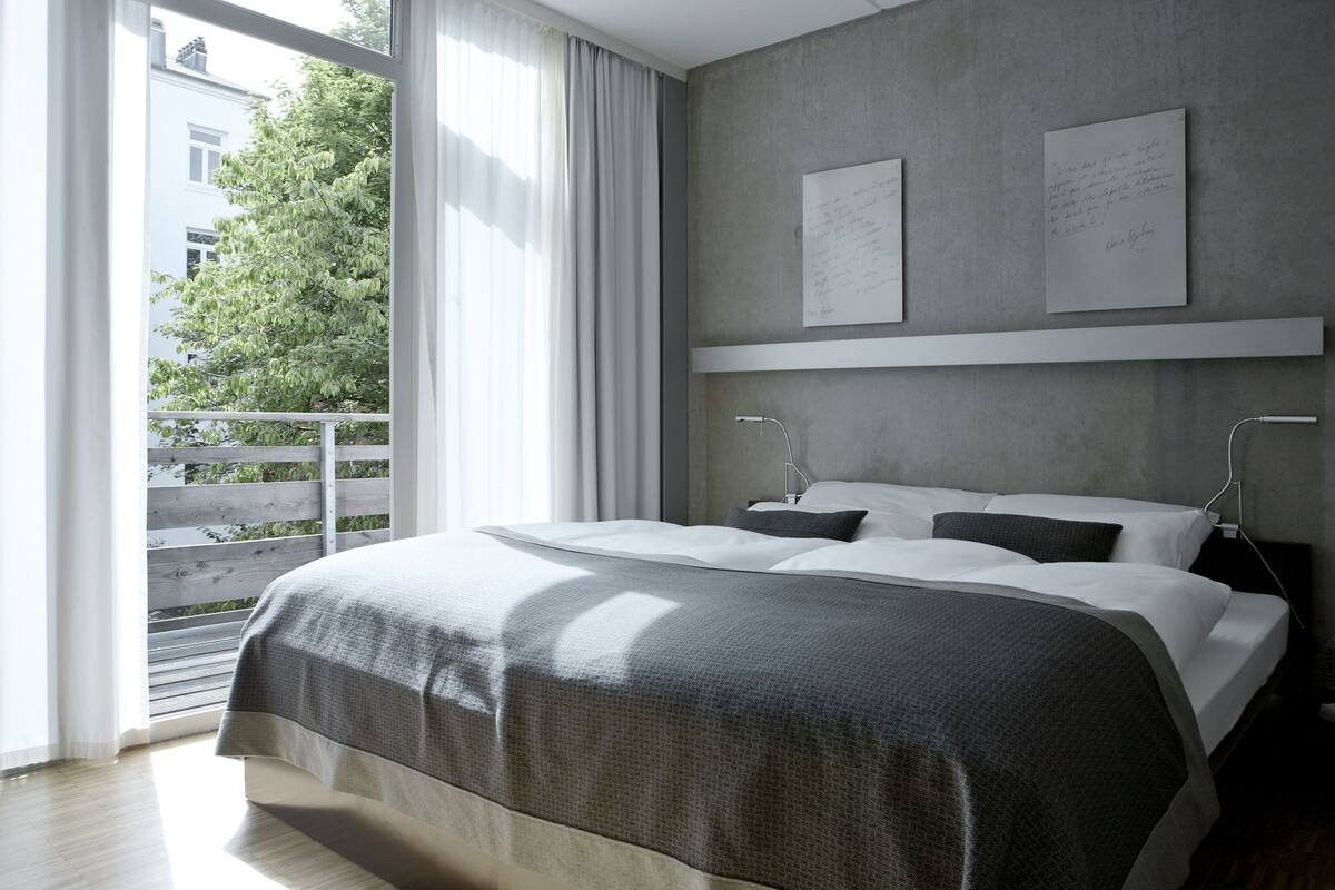 A modern bedroom with a large bed, a view of the outdoors, and a note on the wall.