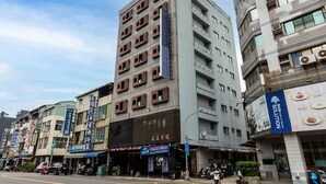 Un immeuble à plusieurs étages dont le rez-de-chaussée est occupé par des locaux commerciaux, notamment un restaurant et divers magasins.