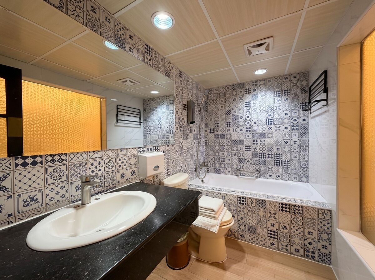 A bathroom with a sink, toilet, and bathtub, featuring patterned tiles and a mirror.