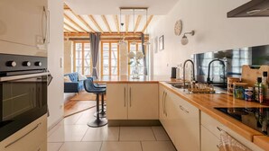A modern kitchen with a wooden countertop, a built-in oven, and a bar stool.