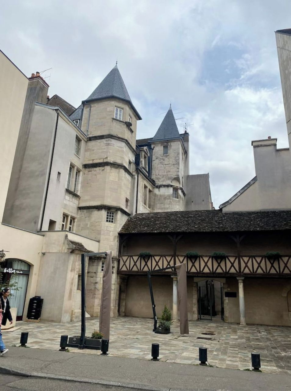 A historic building with a tower, a covered walkway, and a street in front.