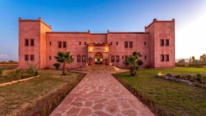 A large, rectangular building with a central entrance, surrounded by a well-maintained lawn and a stone pathway leading to the entrance. - Domaine Marrakech Hacienda a great place to party (Marrakech)