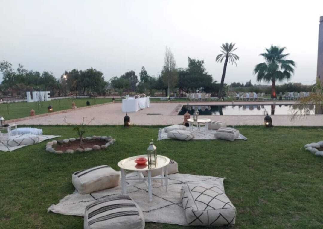 Un espace extérieur aménagé avec des tables et des coussins, un petit étang et des palmiers.