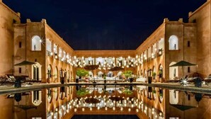 A courtyard with a reflective pool, surrounded by buildings with arched windows and outdoor seating areas. - Domaine Marrakech Hacienda a great place to party (Marrakech)