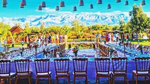 An outdoor dining area with tables and chairs, a mountainous backdrop, and hanging lanterns. - Domaine Marrakech Hacienda a great place to party (Marrakech)
