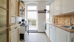 A kitchen with white cabinetry, a patterned floor, and a view to the outside. - Vacation apartment Herrenzimmer with fireplace and terrace (Annaberg-Buchholz)