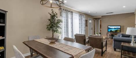 Una sala de estar moderna con un sofá, un televisor y un comedor con una mesa y sillas.