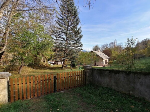 A rural property with a wooden fence, a stone wall, and a small house with a sloped roof. - House with large plot and mountain views (Le Noyer)