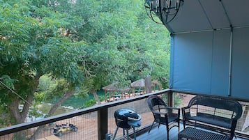 Ein Balkon mit Grill, Korbmöbeln und Blick auf einen Fluss und Bäume.