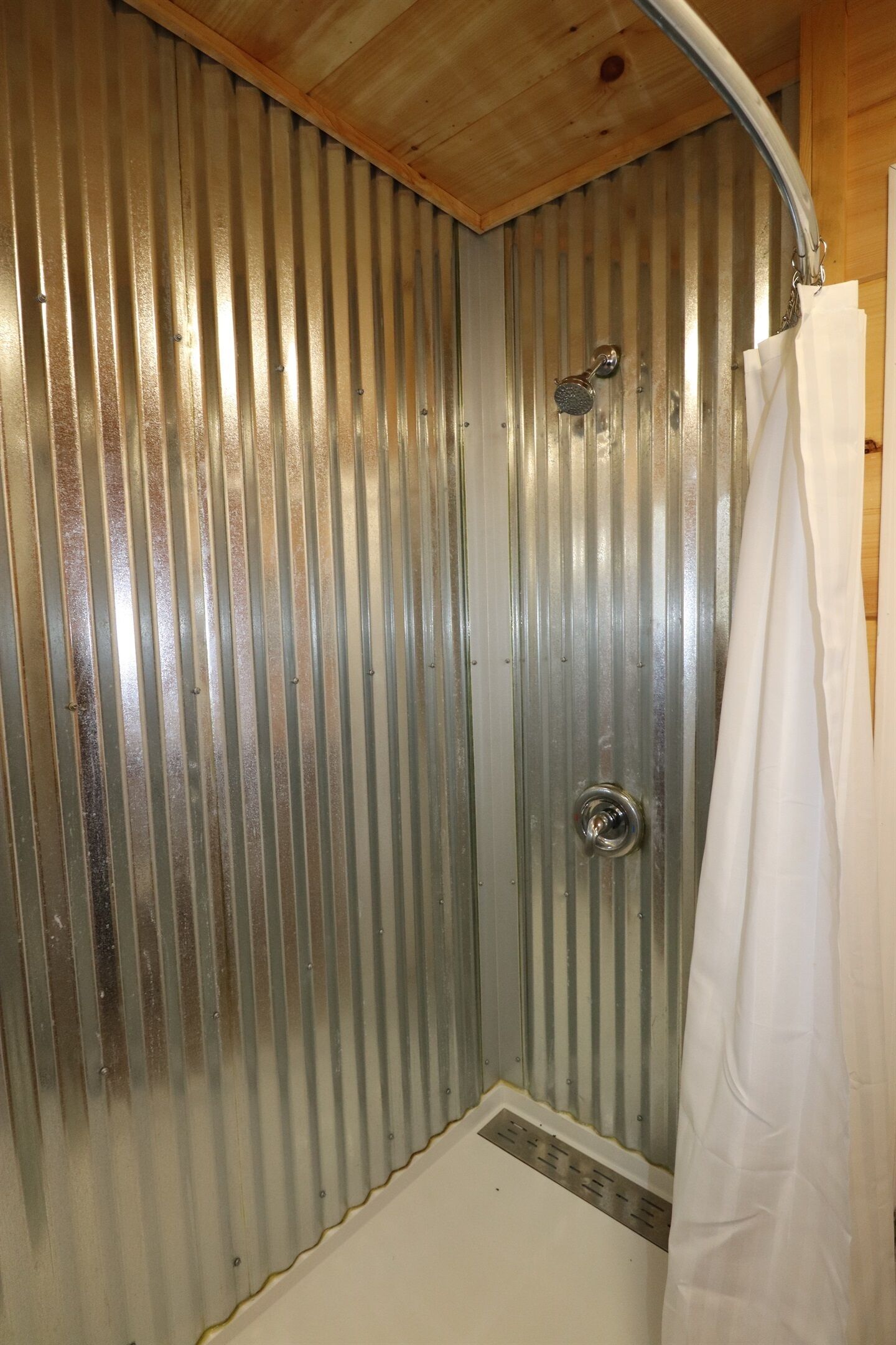 Une douche avec un plafond en bois et des murs en métal ondulé.