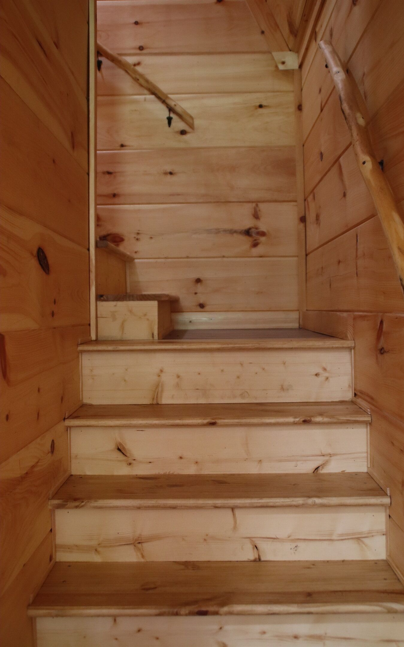 A wooden staircase with a handrail, leading to a landing with a small table.