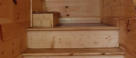 Un escalier en bois, doté d’une rampe, mène à un palier où se trouve une petite table.