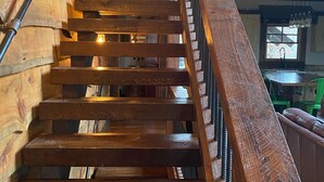 A wooden staircase with a metal handrail, leading to an upper floor. - Parade of Homes Cabin w/hot tub, outdoor fireplace, community riverfront!  (Blue Ridge)