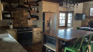 A kitchen with a central island, wooden cabinets, a stove, and a refrigerator. - Parade of Homes Cabin w/hot tub, outdoor fireplace, community riverfront!  (Blue Ridge)