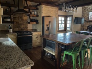 A kitchen with a central island, wooden cabinets, a stove, and a refrigerator.