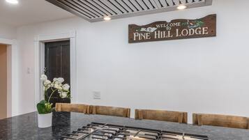 A kitchen with a stainless steel range hood, a digital clock, and a welcome sign for Pine Hill Lodge.