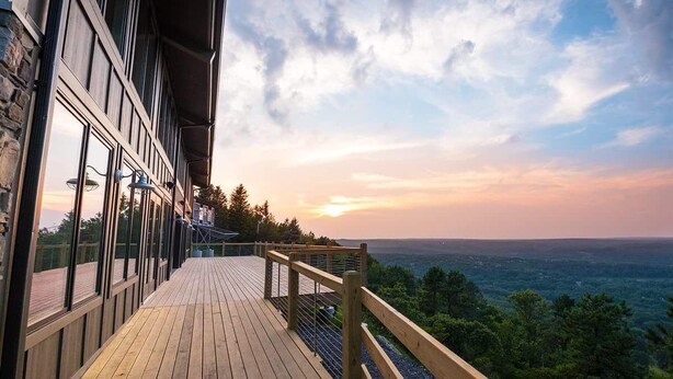 Una terraza de madera con barandilla que da a un paisaje boscoso.