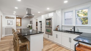 Una cocina moderna con armarios blancos, electrodomésticos de acero inoxidable y una zona de comedor de madera.