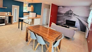 Una cocina moderna con comedor, sofá y un mural de una escena costera.