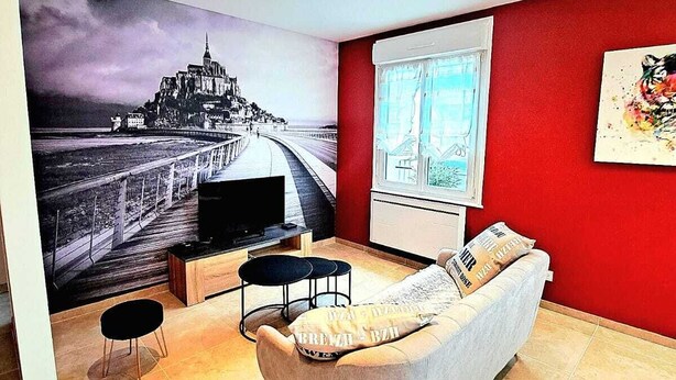 Una sala de estar moderna con un mural grande en la pared, un sofá cómodo, un televisor y una ventana con cortinas.