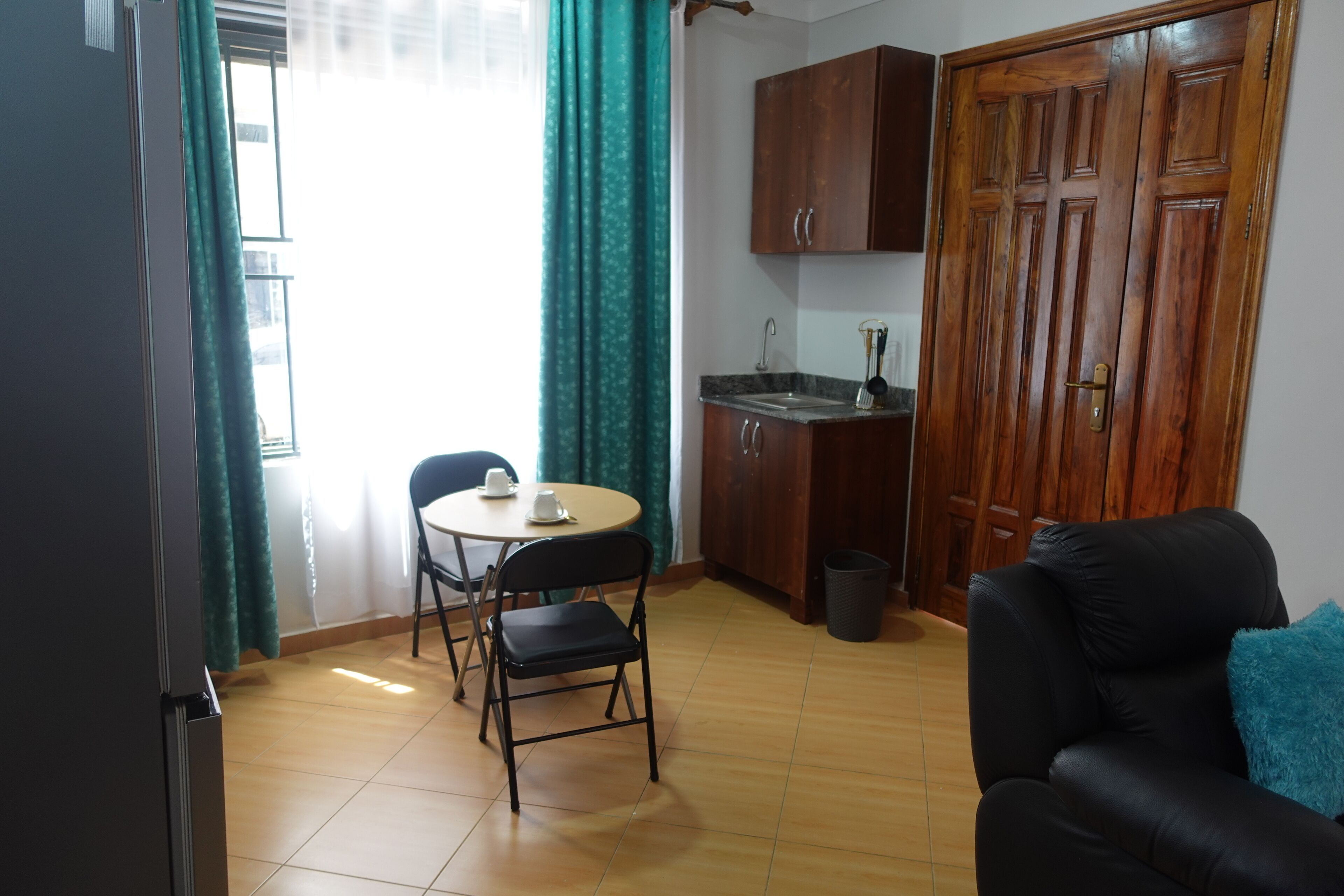 Un espace de vie compact comprenant un coin repas, une kitchenette et un canapé en cuir noir.
