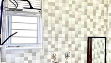 A bathroom with a checkered tile backsplash, a window, a sink, and a toilet.