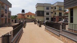 A residential area with multi-story buildings, a paved walkway, and a gated entrance. - C&A Orchid Apartments (Kampala)