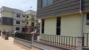 A multi-story residential building with balconies, a paved driveway, and a parked car. - C&A Orchid Apartments (Kampala)