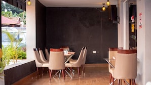 A dining area with a dark wall, wooden floor, and modern chairs. - Romeos Hotel (Kampala)