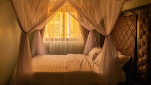 A bed with a canopy, a window with blinds, and a wooden headboard. - Romeos Hotel (Kampala)
