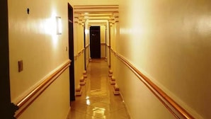 A long, narrow hallway with a tiled floor and a central staircase leading to a dark door at the end. - Romeos Hotel (Kampala)