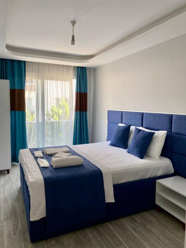 Una habitación de hotel moderna con una cama grande, un cabecero y vistas a zonas verdes.