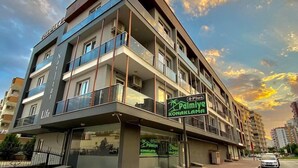 A multi-story hotel with balconies, a sign for "Palmive Konaklama," and a clear sky. - Palmiye Gold (Mersin)