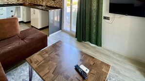 A modern living room with a brown leather sofa, a wooden coffee table, and a TV mounted on the wall. - Palmiye Gold (Mersin)