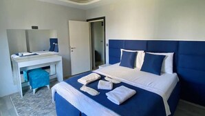 A modern bedroom with a large bed, a desk, and a mirror. - Palmiye Gold (Mersin)